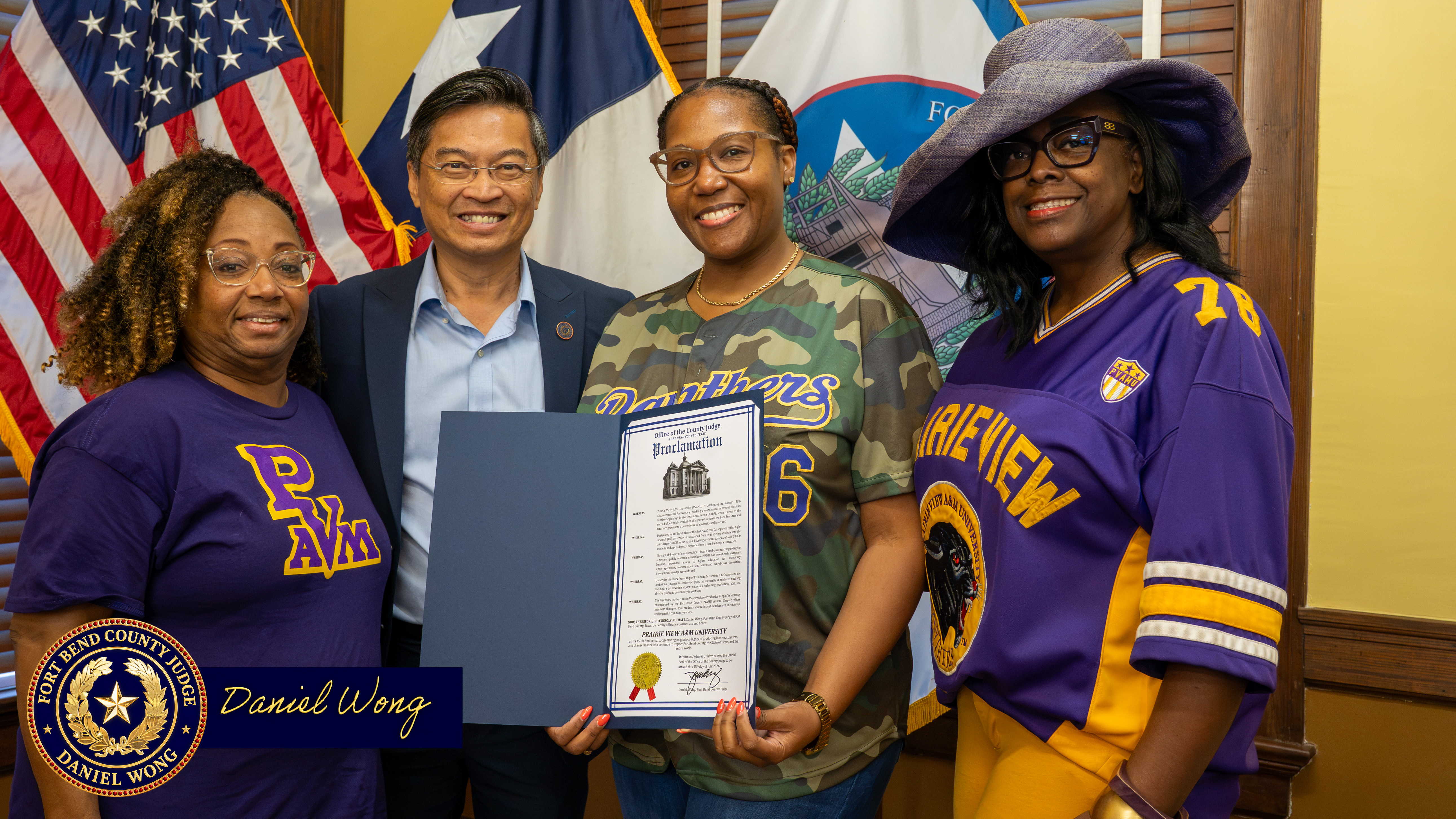 Judge Dainel Wong taking group photo with alumni of Prairie View A & M University behind the flags